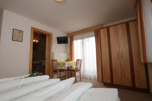 a room with four white beds and a table and a window at Haus Rosi in Umhausen
