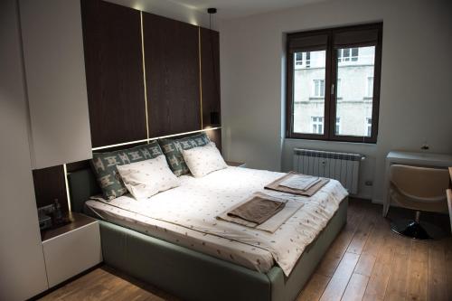 a bedroom with a bed with a headboard and a window at Apartment Rotonda in Sofia