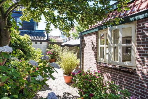 a garden with flowers and a window on a brick house at Near the Beach in Zandvoort