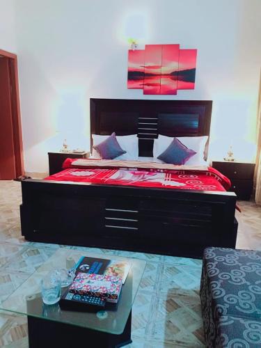a bedroom with a large bed with a red bedspread at Pyramid International Guest House in Islamabad