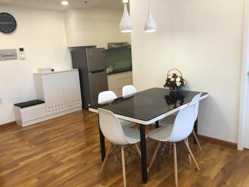 a dining room with a black table and white chairs at Nancy Vung Tau in Vung Tau