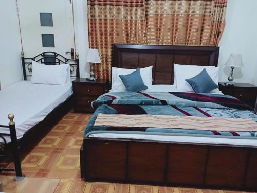 a bedroom with two beds with blue and white pillows at Pyramid International Guest House in Islamabad