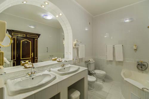 a bathroom with two sinks and a toilet and a mirror at Aurelius Imparatul Romanilor Hotel & SPA in Poiana Brasov