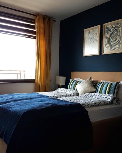 a bedroom with a bed with blue walls and a window at Apartment "Central" in Yambol