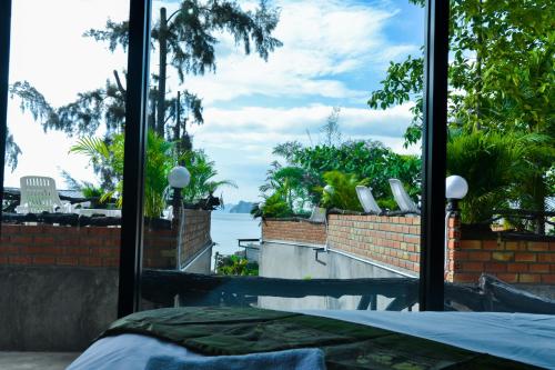 a bedroom with a view of the water through a window at Baan Tubkaek Hotel in Tab Kaek Beach