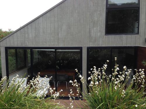 a house with black windows and white flowers in front of it at Southern Ocean Villa 9 in Port Campbell