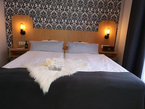 a bed with a white comforter and a book on it at Hotel am Kurpark in Bad Lauterberg