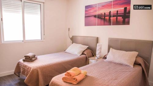 バレンシアにあるAPARTMENTSUITESPAIN ATIC PANORAMIC Beachのベッドルーム1室(ベッド2台、タオル付)