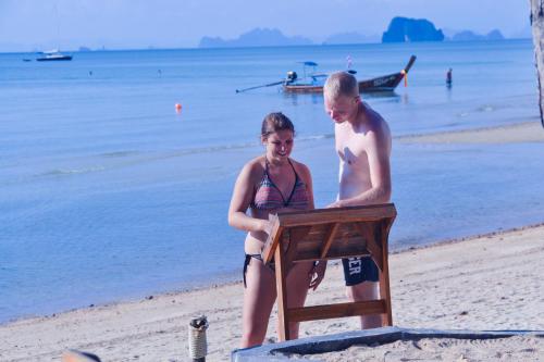 a man and a woman standing on a beach at Baan Tubkaek Hotel in Tab Kaek Beach