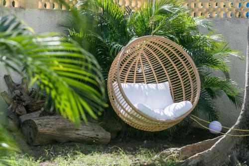 a wicker chair sitting in front of some plants at Hevea Hotel in Grand Case