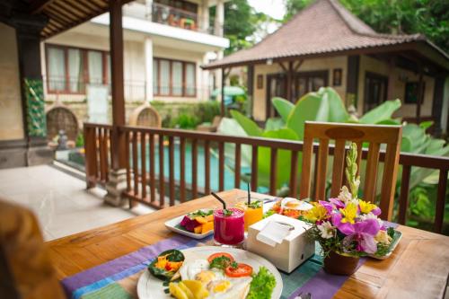 a table with a plate of eggs and fruit on it at Ayu Duwur Beji in Ubud