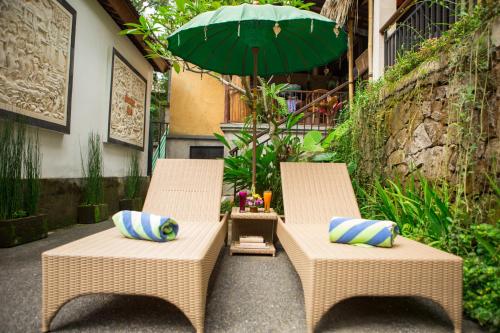 two wicker chairs and an umbrella on a patio at Ayu Duwur Beji in Ubud