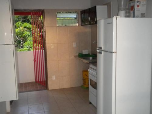 a kitchen with a white refrigerator and a sink at Cobertura paraiso Cacoes in Jaguaripe