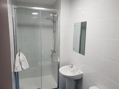a white bathroom with a shower and a sink at The Kingstanding Inn in Birmingham