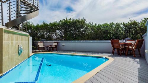 a swimming pool on a deck with a table and chairs at Knysna Pearl View Guest House in Knysna