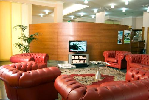 a waiting room with red leather chairs and a flat screen tv at Hotel San Michele in LʼAquila