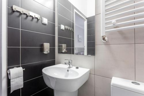 ein weißes Badezimmer mit einem Waschbecken und einem Spiegel in der Unterkunft Babel Hostel in Breslau