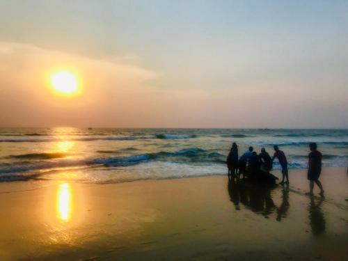 a group of people standing on the beach at sunset at LaligurasVilla Beachside Escape - 100m to Beach in Candolim
