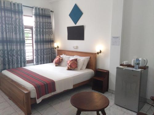 a bedroom with a bed and a table and a window at Hotel Ocean View Cottage in Hikkaduwa