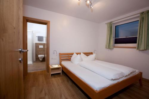 ナウダースにあるApart Bergzeitのベッドルーム1室(白いシーツ付きのベッド1台、窓付)