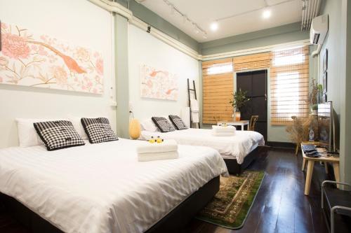 two beds in a room with white sheets at The Orientale Hostel in Bangkok