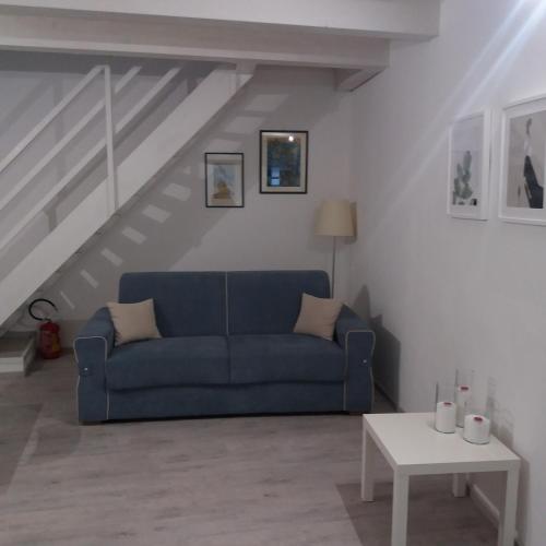 sala de estar con sofá azul y escaleras en La Corte di Aci, en Acireale