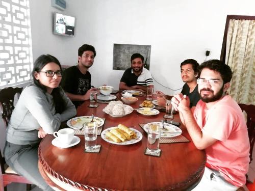 a group of people sitting around a table with food at Old Parkland Hostel in Galle