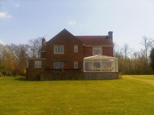 a large brick house with a greenhouse in the yard at Plumpton House in Ashford