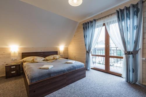 a bedroom with a bed and a large window at Chatka u Stanka z bilardem , sauną i jacuzzi in Biały Dunajec