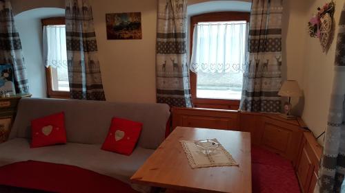 a living room with a couch and a table and windows at Casa di Chiara in Padola