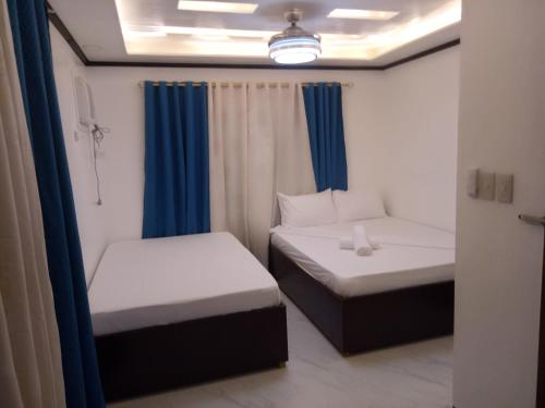 two beds in a small room with blue curtains at Aquilah Homestay Inn in Coron