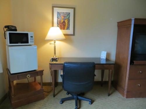 a room with a desk with a microwave and a chair at Cameo Motel - Portland in Portland