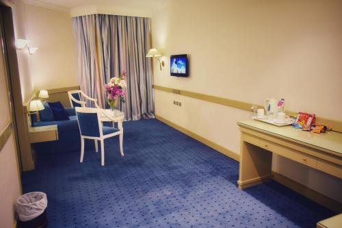 a hotel room with a table and a chair and a room at Romance Alexandria Hotel in Alexandria