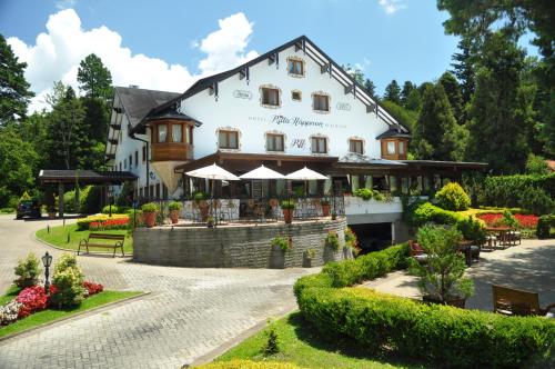 a large white building with umbrellas in front of it at Hotel Ritta Höppner in Gramado