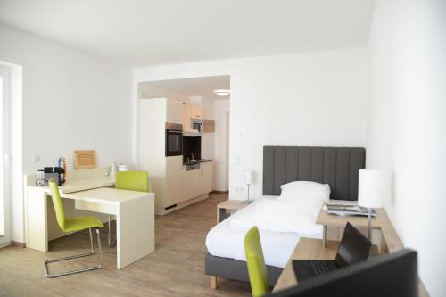 a bedroom with a bed and a desk with a laptop at Adapt Apartments Giessen in Gießen