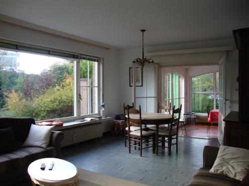 uma sala de estar com uma mesa e cadeiras e uma grande janela em Villa Donnylaan em De Panne