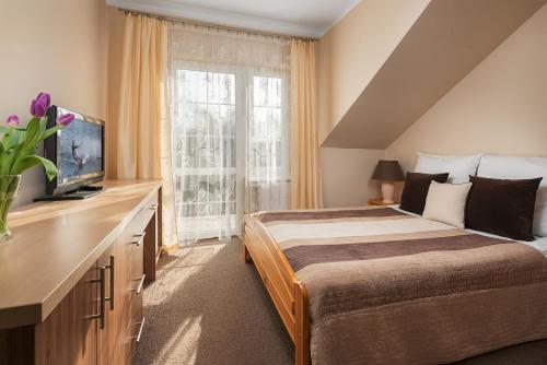 Un dormitorio con una cama y un televisor y una ventana. en RizaVilla, en Krynica Morska