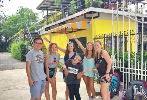 a group of people standing in front of a yellow building at Mango House in Sukhothai