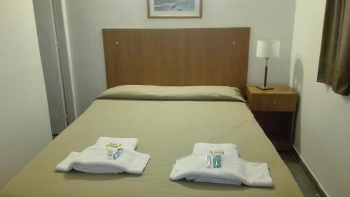 a bed with two folded towels on top of it at Hotel Caribe in Mar del Plata
