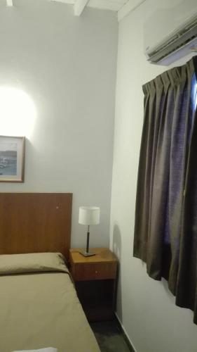 a bedroom with a bed and a window and a lamp at Hotel Caribe in Mar del Plata