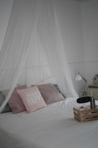 a white bed with a white canopy and pink pillows at Casa de férias Josefa D´Óbidos in Óbidos