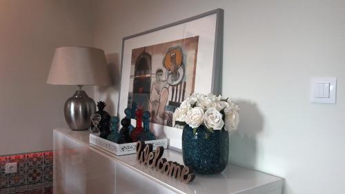 a table with a vase with flowers and a picture at Lx Art Flats | Flat Two in Lisbon