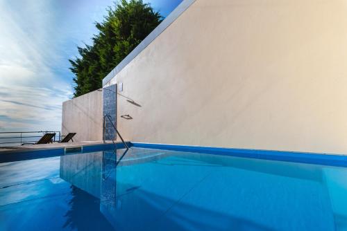una piscina accanto a un muro bianco di Calheta Holiday Houses ad Arco da Calheta