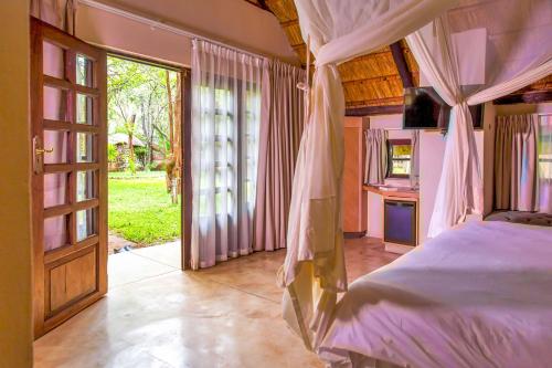 1 dormitorio con 1 cama y puerta abierta en The Royal Sichango Village en Livingstone