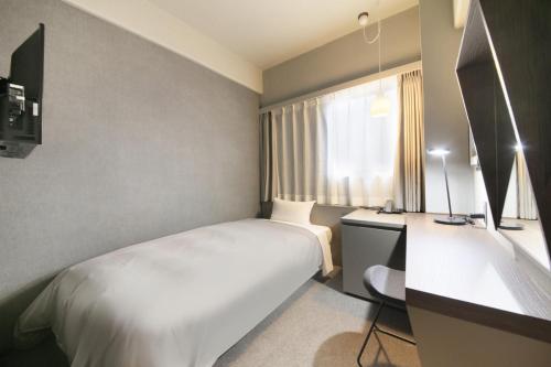 a bedroom with a bed and a desk and a window at Center Hotel Tokyo in Tokyo