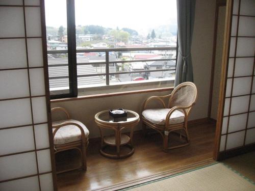 a room with two chairs and a table and a window at Hotel Kinu in Nikko