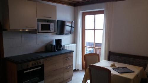 a small kitchen with a table and a microwave at Cafe Pension Erbhof in Kartitsch