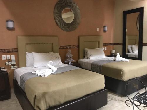 two beds in a hotel room with towels on them at Villas y Suites Paraiso del Sur in Cuernavaca