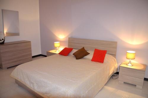 シラクーサにあるAppartamento Ortigia Giulianaのベッドルーム1室(赤い枕とランプ2つ付)
