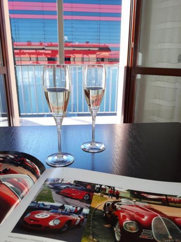 dos copas de vino sentadas en una mesa con una revista en Maranello Suite, en Maranello